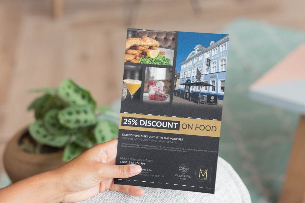 A person holding up a brochure with a picture of a restaurant.