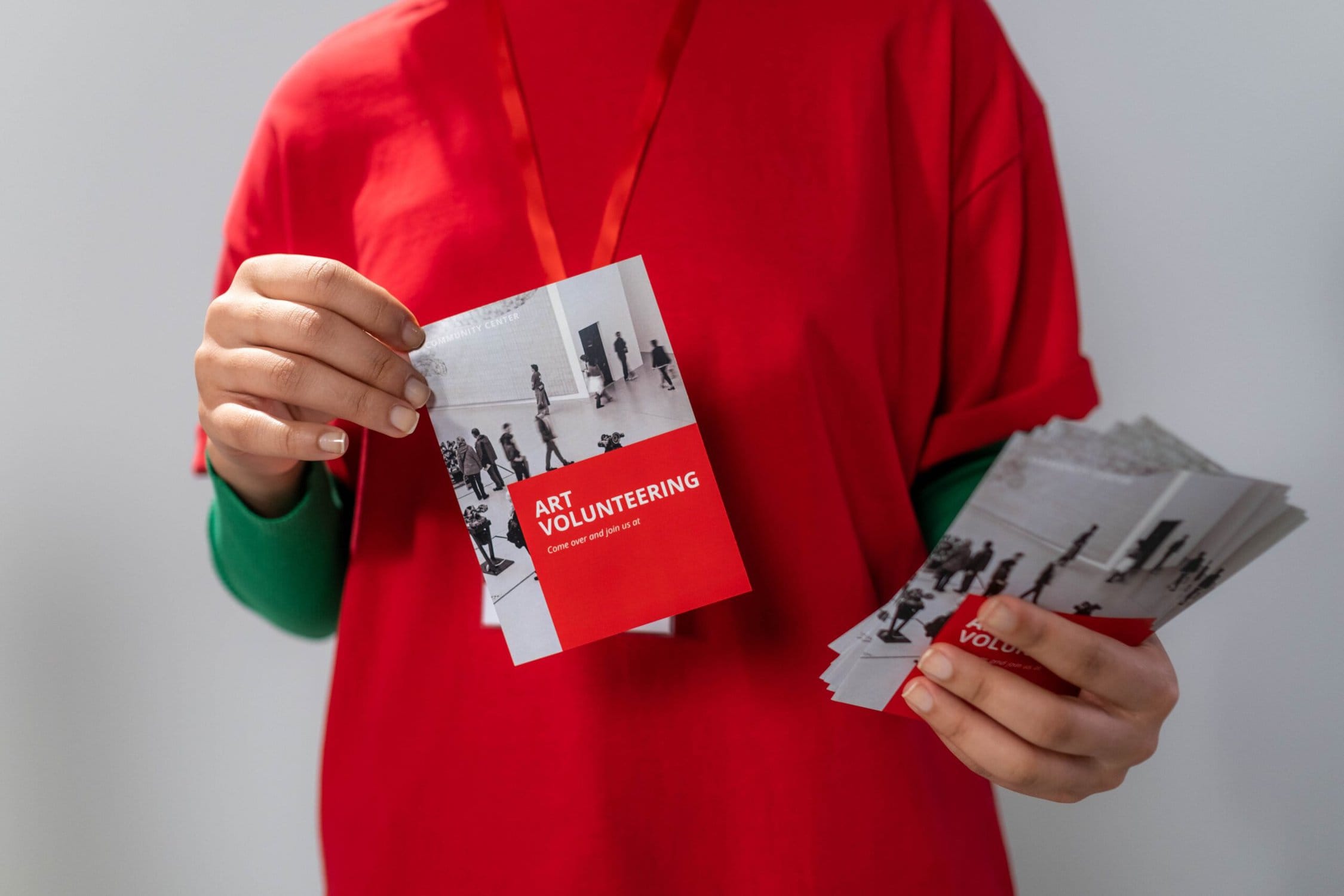 A woman holding up a red t - shirt and a card.